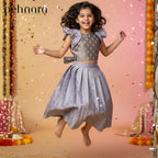 Child in a gray dress with ruffled sleeves and a pleated skirt, jumping in front of a decorative background with lights and confetti.