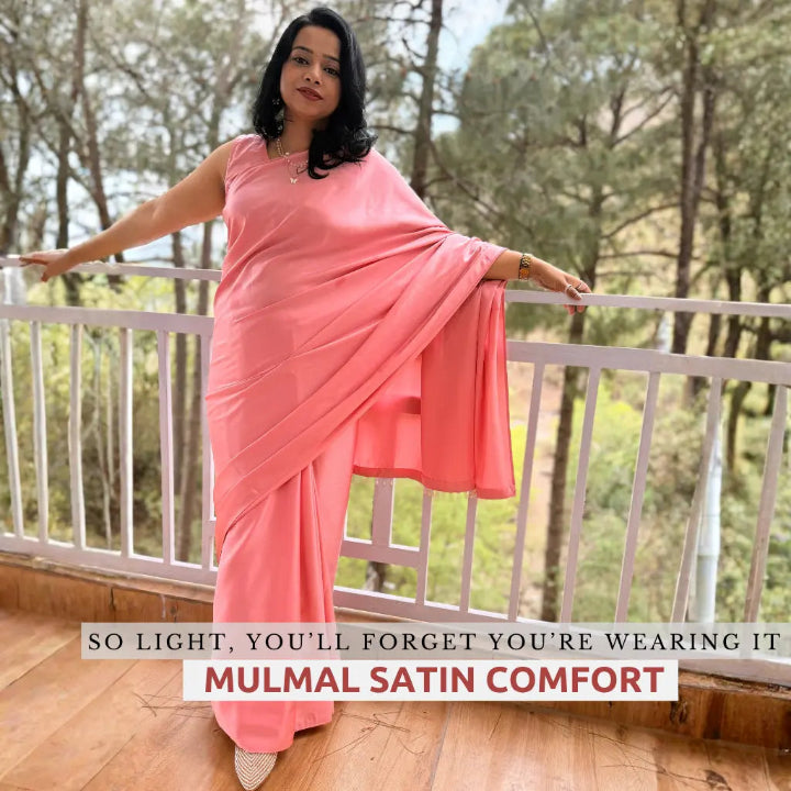 Woman in a pink saree standing on a balcony with trees in the background