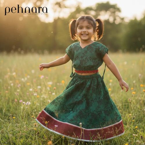 Young girl in a green dress with red trim running through a field of flowers, with 'pehnara' branding.