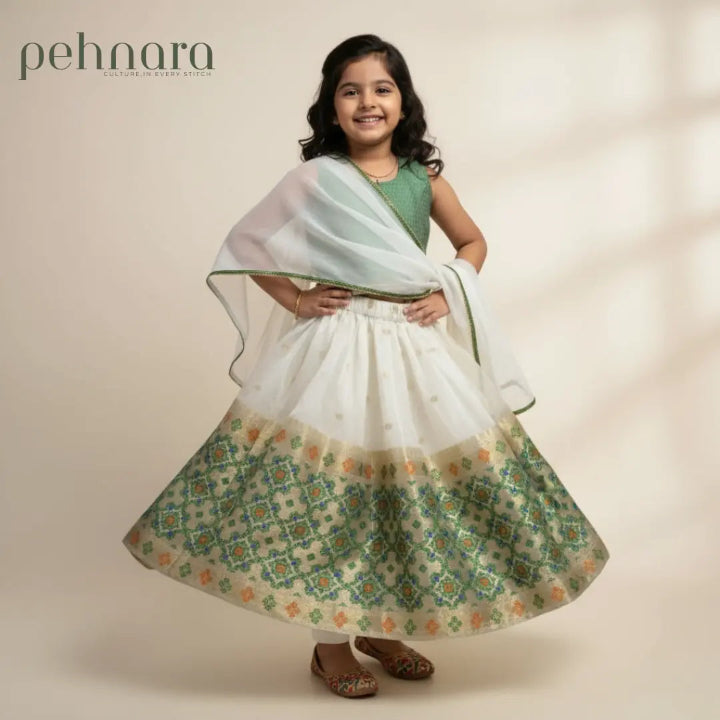 Young girl wearing a traditional outfit with a floral patterned skirt and white shawl, on a plain background.